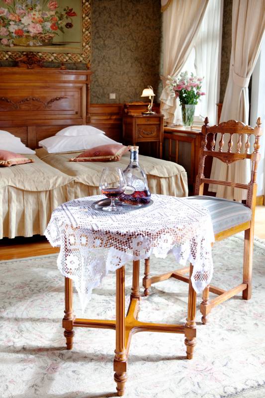 Pałac w Czarnym Lesie nr 6 (Sypialnie z dwoma łóżkami pojedynczymi, na środku mały okrągły stolik z krzesłem, na stoliku karafka z winem i lampką z winem)