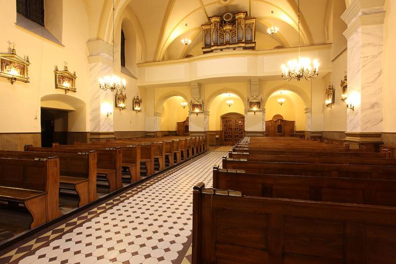 Kościół p.w. Św. Mikołaja nr 3 (Wnętrze Kościoła. Brązowe ławki ułożone w dwóch rzędach. W tle organy, wejście do kościoła oraz dwa konfesjonały. Jasne ściany z obrazami.)