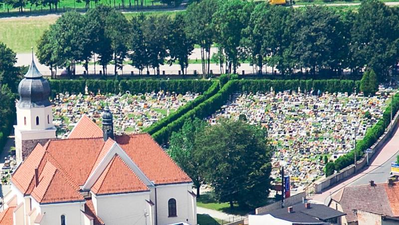 Cmentarz rzymsko-katolicki przy kościele p.w. Św. Jakuba Starszego (Widok z góry na cmentarz. Cmentarz otoczony krzewami. W tle drzewa. Widoczny fragment Parafii.)