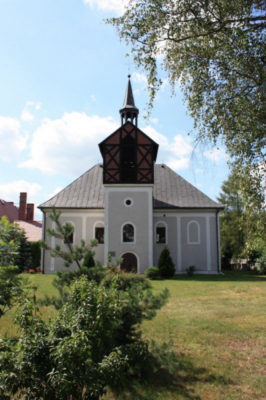 Kościół Opatrzności Bożej w Piasku (Szary Kościół za drzewami, widok na wieżę z dzwonem, wokół trawa)