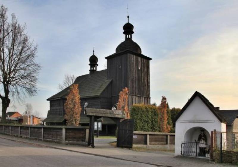 Kościół Św. Marcina w Cieszowej nr 1 (Drewniany kościół otoczony płotem z otworzoną bramą i krzewami. Z prawej strony - kaplica. W tle drzewa.)