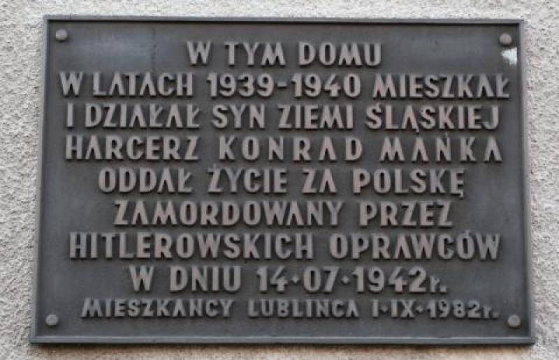 Tablica upamiętniająca Konrada Mańkę w Lublińcu nr 1 (Czarna tablica pamiątkowa na jasnym tle. Na niej napis W tym domu w latach 1939-1940 mieszkał i działał syn Ziemi Śląskiej harcerz Konrad Mańka Oddał życie za Polskę Zamordowany przez hitlerowskich oprawców w dniu 14.07.1942 r. Mieszkańcy Lublińca 1.IX.1)