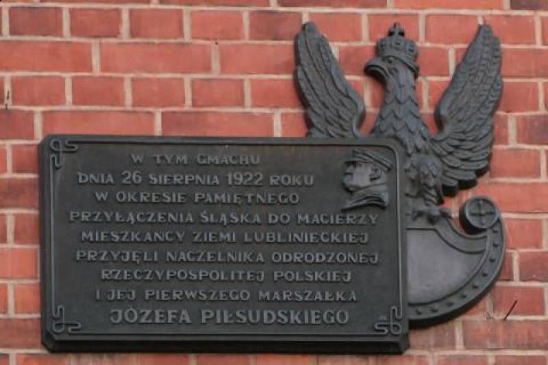 Tablica na budynku Starostwa Powiatowego nr 1 (Tablica pamiątkowa w ciemnoszarym kolorze na ceglanym tle. Z prawej strony postać orła.)